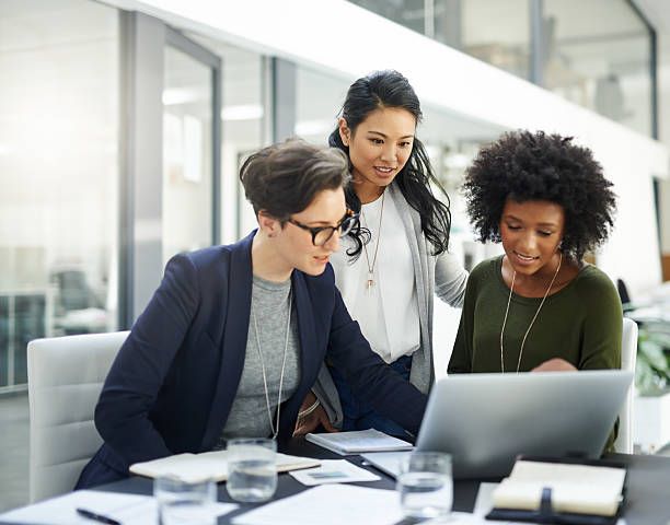 Shot of a group of businesswomen using a laptop during a meeting at work