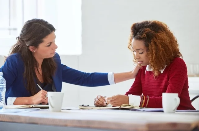 A woman reassures a female employee to quell job insecurity doubts.