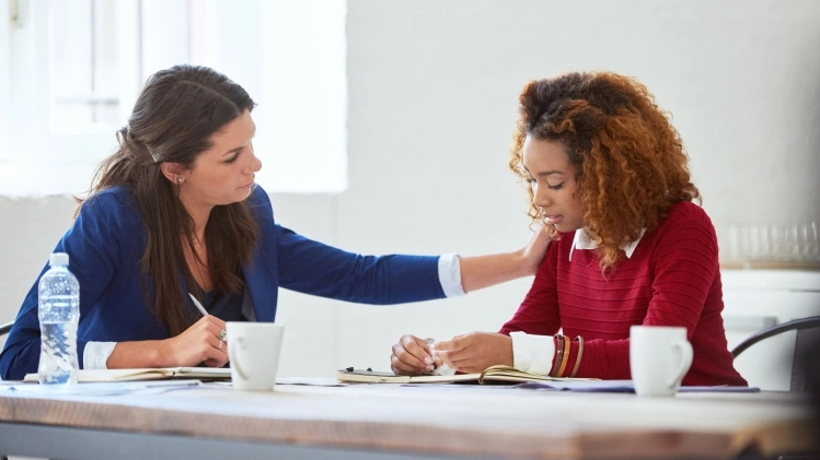 A woman reassures a female employee to quell job insecurity doubts.